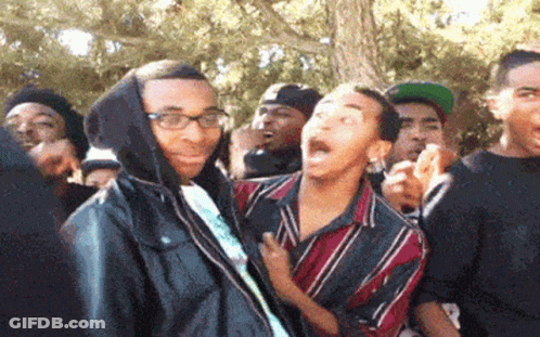 Man In Hooded Jacket Surrounded By Crowd GIF
