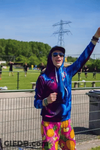 Man In Hoodie And Pineapple Shorts In Field GIF