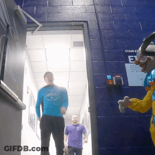 Man In Hornets Shirt Walking Next To Clown GIF
