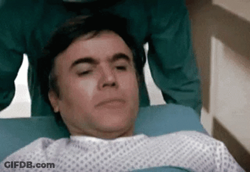 Man In Hospital Gown Laying With Eyes Closed GIF