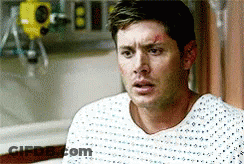 Man In Hospital Gown Sitting In Bed Looking At Camera GIF