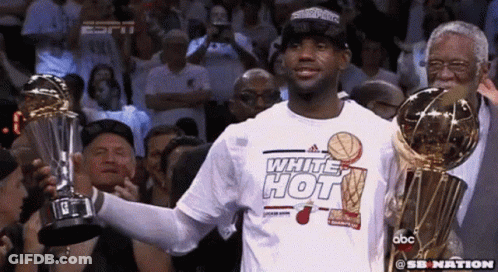 Man In Hot White Shirt Holds Two Trophies Before Crowd GIF