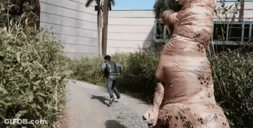 Man In Inflatable T-Rex Costume Running GIF