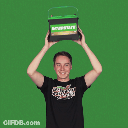 Man In Interstate Batteries Shirt Holding Green Battery Over Head GIF