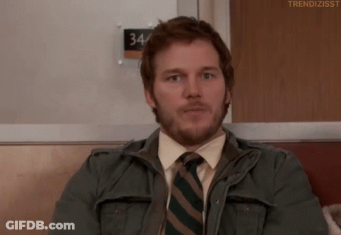 Man In Jacket And Tie Sitting By 34 Sign GIF