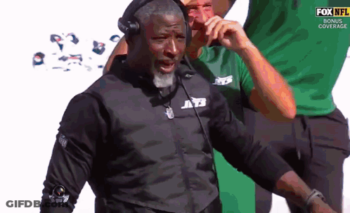 Man In Jets Jacket Talking On Phone GIF