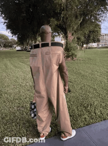 Man In Jumpsuit With Belt Standing In Park GIF