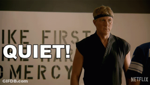 Man In Karate Uniform In Front Of Quiet Sign GIF
