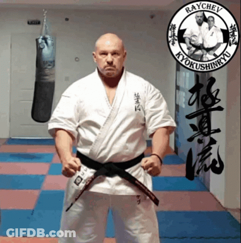 Man In Karate Uniform In Front Of Raychev Sign GIF