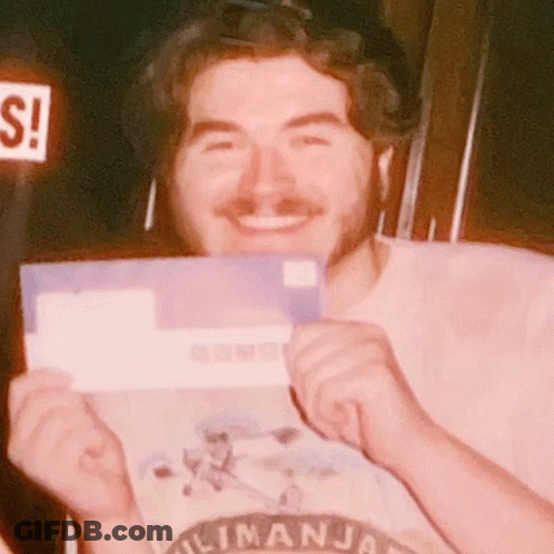 Man In Kilimanjaro Shirt Smiling Holding Purple Envelope GIF