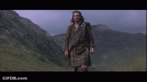 Man In Kilt In Field With Mountains GIF