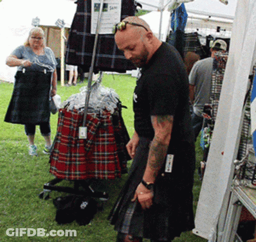 Man In Kilt In Front Of Kilt Display GIF