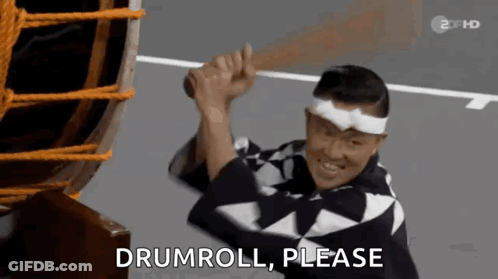 Man In Kimono Holding Drum Saying Drumroll Please GIF