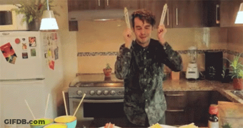 Man In Kitchen Holding Chopsticks To Ears GIF