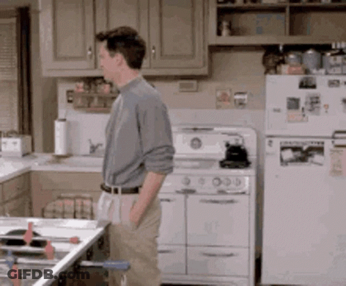 Man In Kitchen Next To Stove And Refrigerator GIF