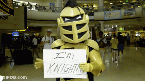 Man In Knight Costume Holding Sign Saying I'm Knightro GIF