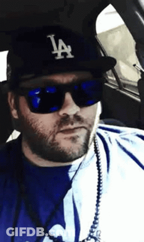 Man In LA Hat And Sunglasses In Car GIF