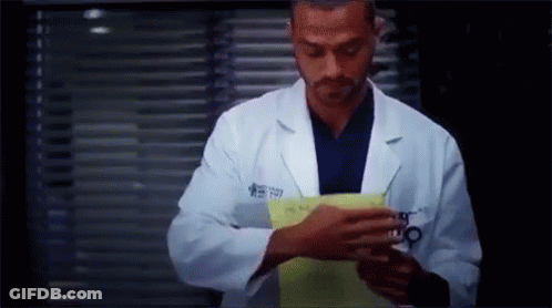 Man In Lab Coat Holding Paper In Front Of Window GIF