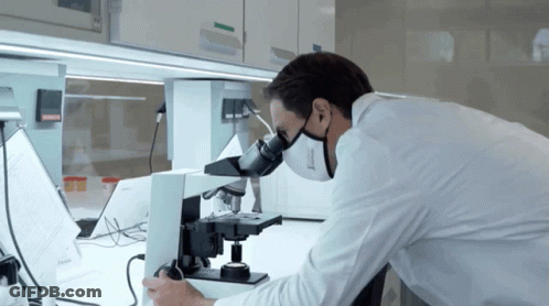 Man In Lab Coat Using Microscope With Mask GIF