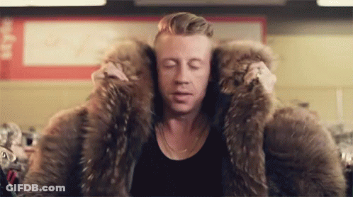 Man In Large Fur Coat Sitting In Store GIF