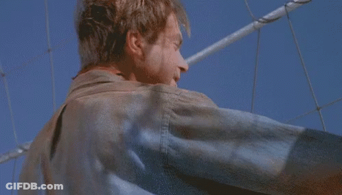 Man In Leather Jacket Against Blue Sky And Fence GIF