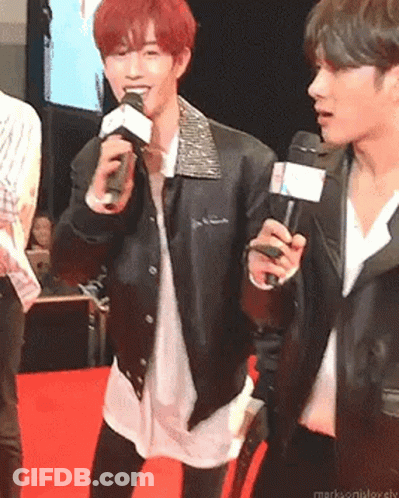Man In Leather Jacket Holding Microphone On Red Carpet GIF