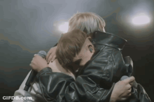Man In Leather Jacket Hugging Another Man Holding Microphone GIF