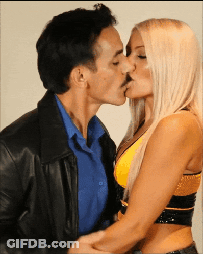 Man In Leather Jacket Kissing Blonde Woman In Yellow GIF