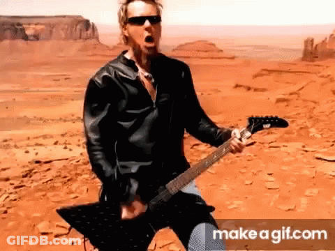 Man In Leather Jacket Playing Guitar In Desert GIF