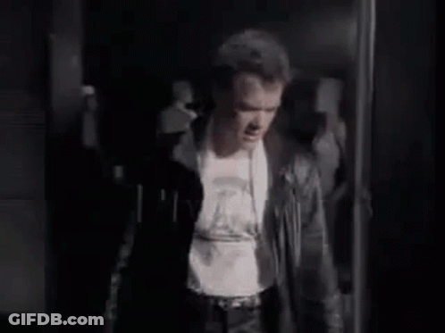 Man In Leather Jacket Standing In Dark Room GIF