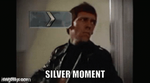 Man In Leather Jacket Standing In Front Of Silver Moment Sign GIF
