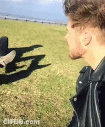 Man In Leather Jacket Standing In Grassy Field With Person GIF