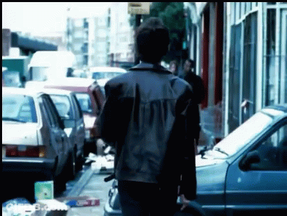 Man In Leather Jacket Walking Down Street GIF
