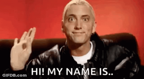 Man In Leather Jacket Waving On Couch GIF