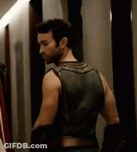 Man In Leather Vest Standing In Hallway GIF