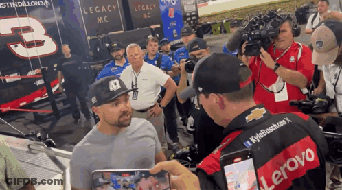 Man In Lenovo Shirt Talking To Man In Hat GIF