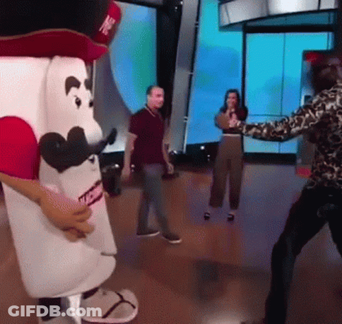 Man In Leopard Print Shirt Standing In Front Of Marshmallow Mascot GIF