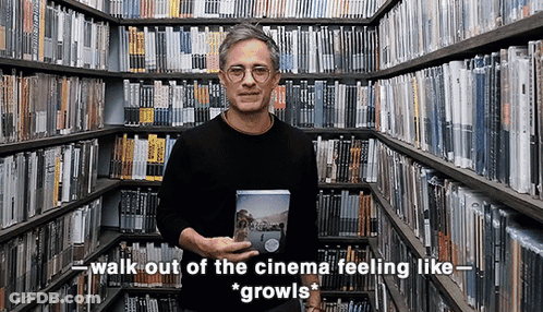 Man In Library Holding DVD Saying Walk Out Of The Cinema Feeling Like Growls GIF