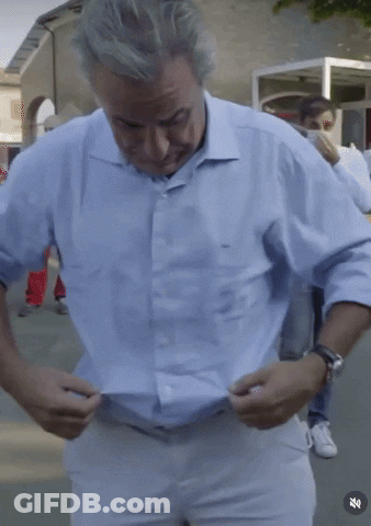 Man In Light Blue Shirt Adjusting White Pants GIF