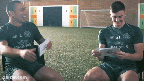 Man In Magners Shirt Sitting Next To Man In New Balance Shirt GIF