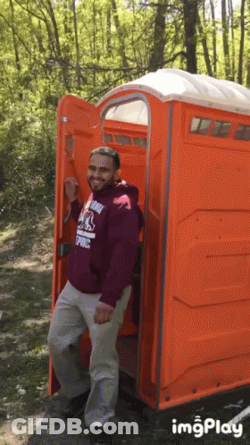 Man In Maroon Hoodie In Orange Public Toilet GIF