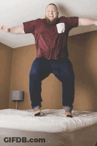 Man In Maroon Shirt Jumping On Bed GIF