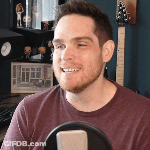 Man In Maroon Shirt Smiling At Microphone GIF