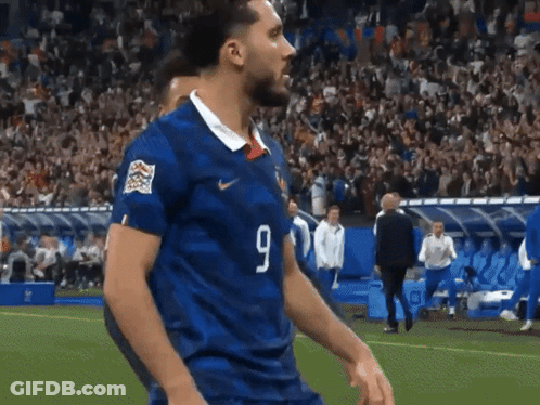 Man In Maroon Shirt Walking On Soccer Field GIF