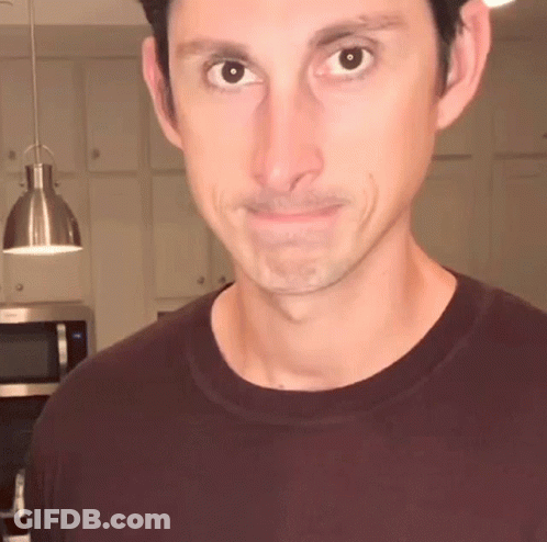 Man In Maroon T-Shirt Looks At Camera GIF