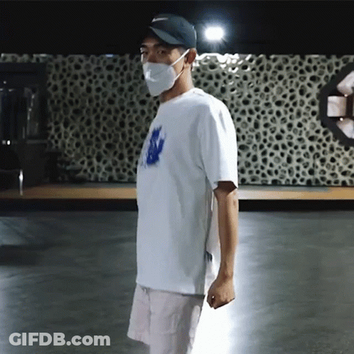 Man In Mask And Hat Standing In Dark Room GIF
