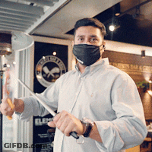 Man In Mask Holding Knife In Front Of Elec Sign GIF