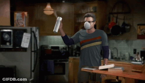 Man In Mask Holding Spray Bottle In Kitchen GIF