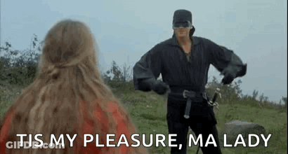 Man In Mask Holding Sword Next To Woman In Field GIF