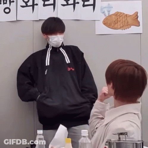 Man In Mask In Front Of Wall With Chinese Writing GIF